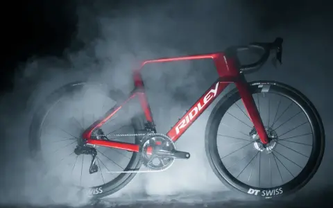 Czerwony rower szosowy Ridley Noah otoczony mgłą, z widocznym napędem i kołami DT Swiss.