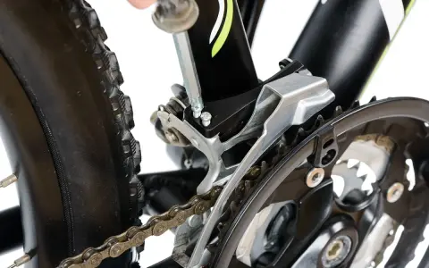 Naprawa roweru: wymiana linki przerzutki przedniej Shimano. Klucz imbusowy dokręca śruby mocujące przerzutkę.