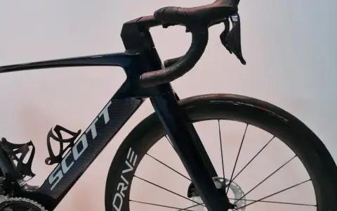 Ciemnoniebieski rower Scott z aerodynamicznym mostkiem i kierownicą. Koła z oponami Schwalbe Pro One.