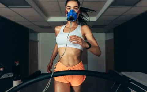 Kobieta w masce tlenowej biegnie na bieżni, badając swoje VO2max.