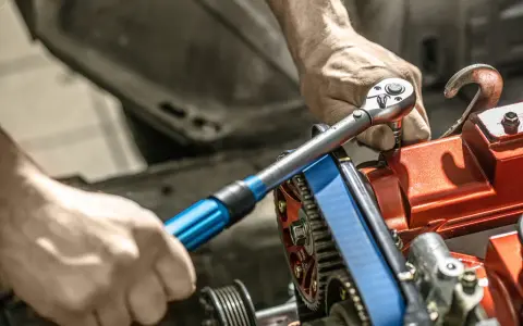 Mechanik używa klucza dynamometrycznego do precyzyjnego dokręcania śrub w silniku. To narzędzie jest kluczowe, by wiedzieć, klucz dynamometryczny co to i jak go używać.