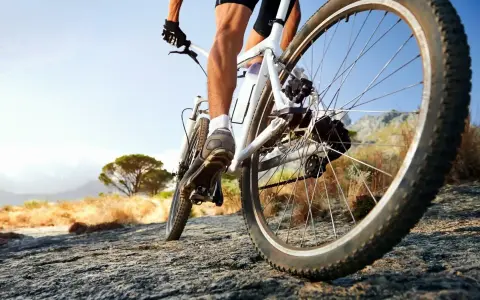 Kolarz na rowerze crossowym lub trekkingowym pokonuje kamienistą ścieżkę w słoneczny dzień.