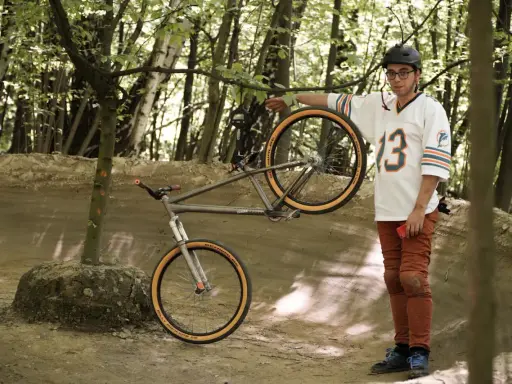 Mężczyzna w koszulce z numerem 13 prezentuje rower, który może być najlżejszym rowerem na świecie.