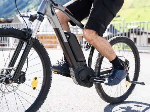 Mężczyzna pedałuje na rowerze elektrycznym, pokazując, jak działa rower elektryczny. Bateria i silnik są widoczne na ramie.