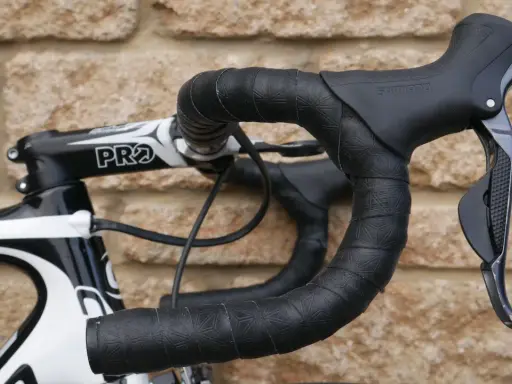 Czarna, wzorzysta owijka na kierownicę roweru szosowego z czarnymi manetkami Shimano.