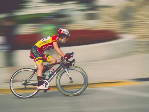 Kolarz w żółto-czerwonym stroju pędzi na rowerze podczas maratonu rowerowego.