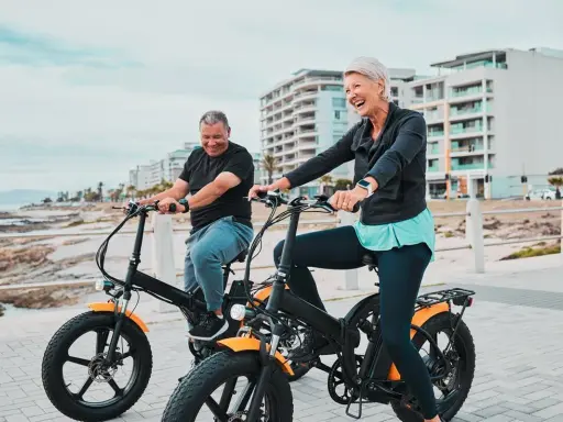 Uśmiechnięci seniorzy na rowerach hybrydowych. Jak działa taki rower? Pomaga w jeździe, dodając mocy!