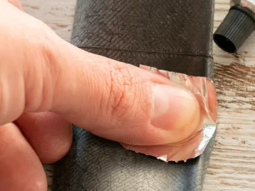 Dłoń przykleja łatkę do dętki roweru z przerzutką w piaście.