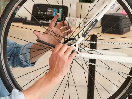 Mężczyzna próbuje zdjąć zębatkę z tylnego koła roweru, używając narzędzia.