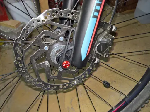Hamulec tarczowy roweru z mocowaniem **center lock**. Widoczna tarcza hamulcowa Shimano, zacisk i szybkozamykacz DT Swiss.
