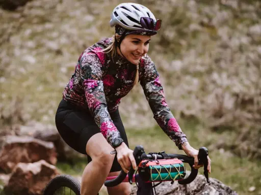 Uśmiechnięta rowerzystka w kwiecistej bluzie pokonuje kolejne kilometry. 100 km na rowerze to wyzwanie, ale radość z jazdy jest widoczna.
