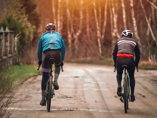 Dwóch rowerzystów w jesiennych strojach, idealnych na 15 stopni. Lekkie kurtki i długie spodnie zapewniają komfort podczas jazdy.