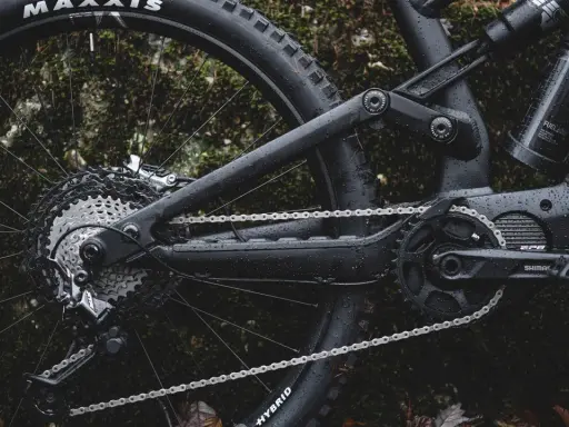 Część roweru elektrycznego z napędem **Shimano EP8** w deszczu. Widoczna kaseta, przerzutka, łańcuch i korba.