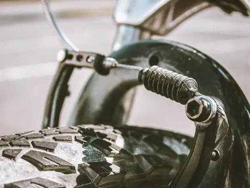Zbliżenie na mechanizm hamulca rowerowego z widoczną sprężyną i linką. Dowiedz się, jak poluzować hamulce w rowerze.