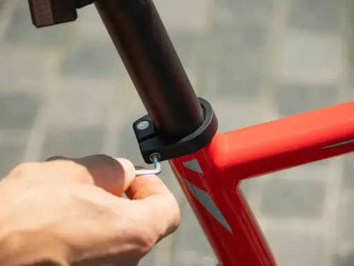 Dłoń dokręca śrubę imbusową mocującą sztycę rowerową. Różne sztyca rowerowa rozmiary są dostępne, aby dopasować się do każdej ramy.
