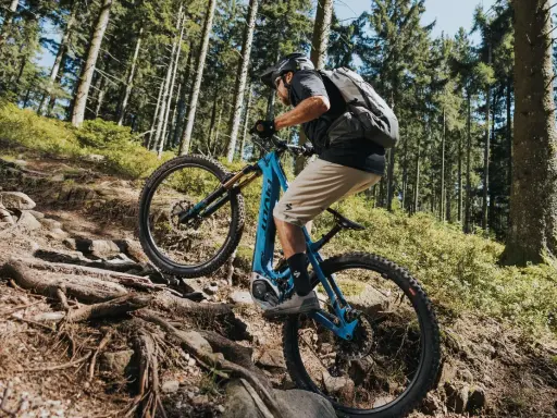Kolarz na rowerze elektrycznym z napędem Bosch Performance Line CX pokonuje kamienisty, leśny szlak.