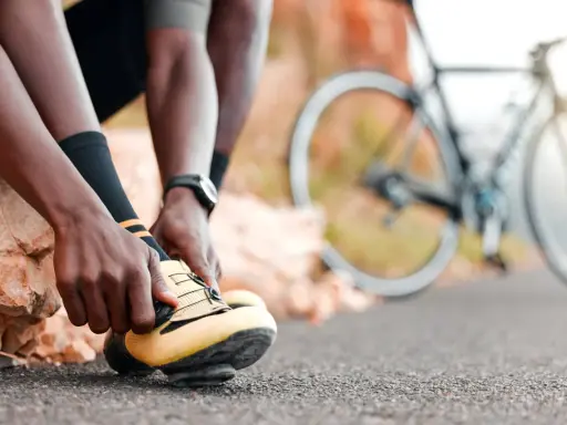 Rowerzysta zapina żółte buty, gotowy na kolejne wyzwania w **sporty rowerowe**. W tle widać rower.