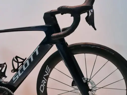 Ciemnoniebieski rower Scott z aerodynamicznym mostkiem i kierownicą. Koła z oponami Schwalbe Pro One.