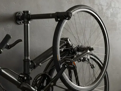 Czarny rower wiszący na ścianie na industrialnym wieszaku. Prosty sposób, jak powiesić rower na ścianie, oszczędzając miejsce.