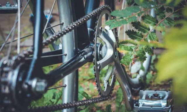 Zbliżenie na mechanizm korbowy i łańcuch rowerowy. Różne rodzaje łańcuchów rowerowych zapewniają płynną jazdę.