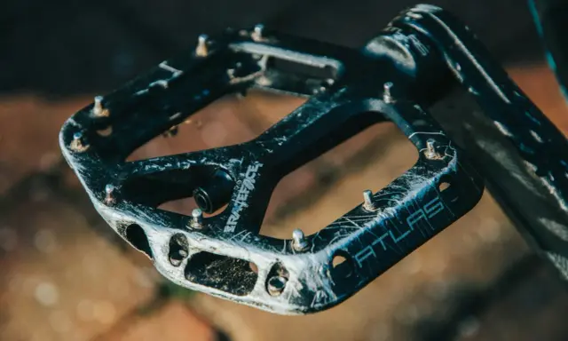Czarne pedały Race Face Atlas, idealne jakie pedały do MTB, z widocznymi śladami użytkowania i pinami.