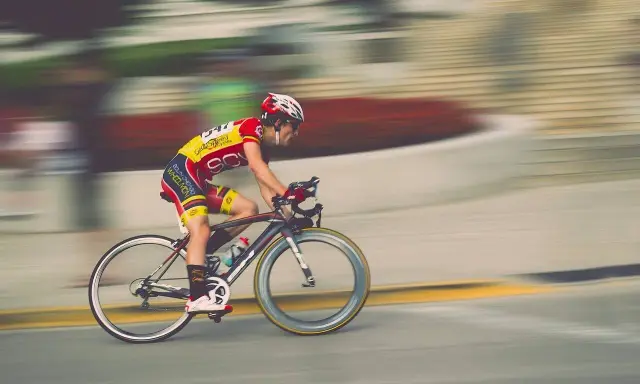 Kolarz w żółto-czerwonym stroju pędzi na rowerze podczas maratonu rowerowego.