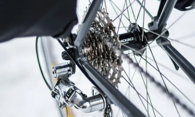 Błyszczący osprzęt Shimano Deore na tylnej przerzutce i kasecie rowerowej.