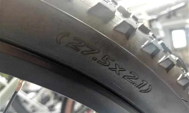 Na oponie rowerowej widoczny napis (27.5x2.1), który pomaga określić, jak zmierzyć rozmiar koła w rowerze.