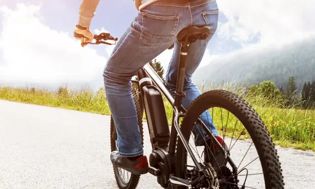 Osoba na rowerze elektrycznym cieszy się jazdą po malowniczej trasie. Dofinansowanie do roweru sprawia, że takie wycieczki są dostępne dla każdego.