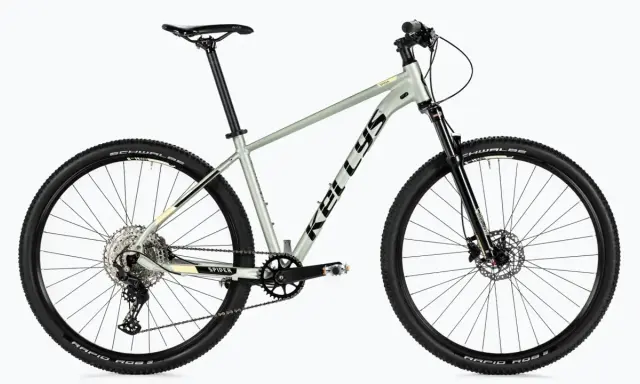 Lekki, szary rower górski Kellys Spider, rower bez amortyzatora, z czarnymi oponami Schwalbe i przerzutkami Shimano.