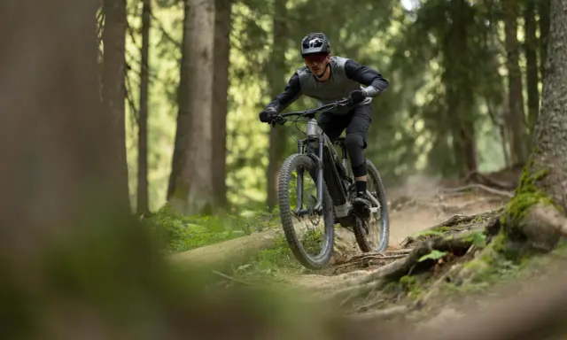 Rowerzysta w kasku i okularach zjeżdża po wyboistej leśnej ścieżce. To właśnie jest **co to enduro** – jazda po trudnym terenie.