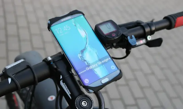 Jaki uchwyt na telefon do roweru? Samsung Galaxy S6 edge+ zamontowany na kierownicy roweru, obok licznika.