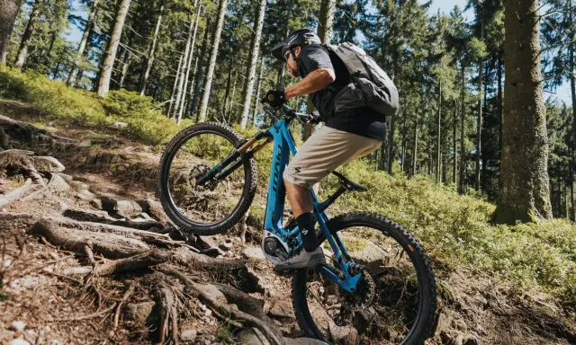 Kolarz na rowerze elektrycznym z napędem Bosch Performance Line CX pokonuje kamienisty, leśny szlak.