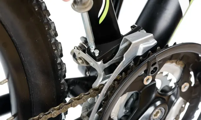 Naprawa roweru: wymiana linki przerzutki przedniej Shimano. Klucz imbusowy dokręca śruby mocujące przerzutkę.