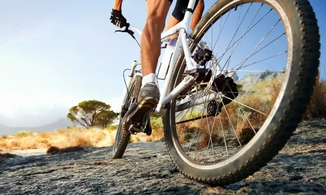 Kolarz na rowerze crossowym lub trekkingowym pokonuje kamienistą ścieżkę w słoneczny dzień.