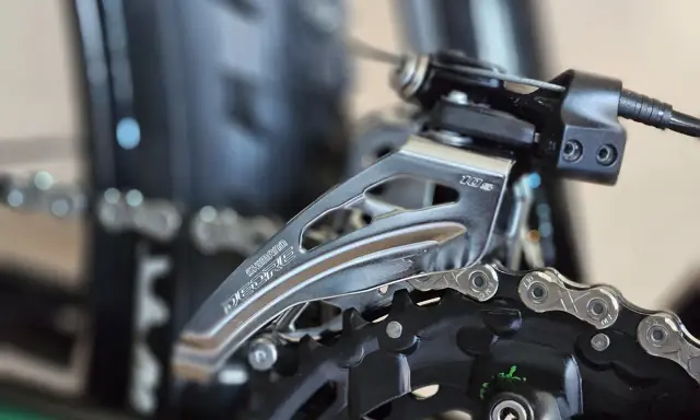 Zbliżenie na przednią przerzutkę rowerową Shimano Deore. Dowiedz się, jak zmieniać przerzutki w rowerze, by jazda była płynniejsza.