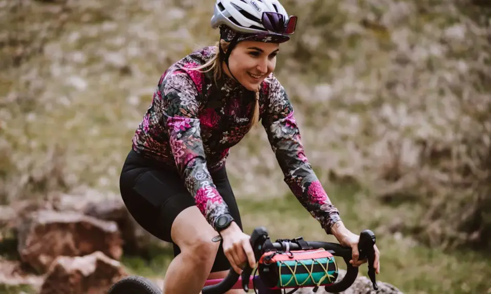 Uśmiechnięta rowerzystka w kwiecistej bluzie pokonuje kolejne kilometry. 100 km na rowerze to wyzwanie, ale radość z jazdy jest widoczna.