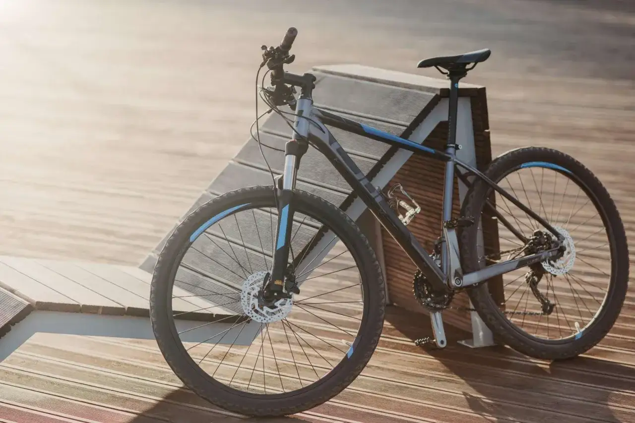 Szary rower z niebieskimi akcentami, z amortyzatorem i tarczowymi hamulcami, idealny na ścieżki. Czy to rower crossowy czy mtb?