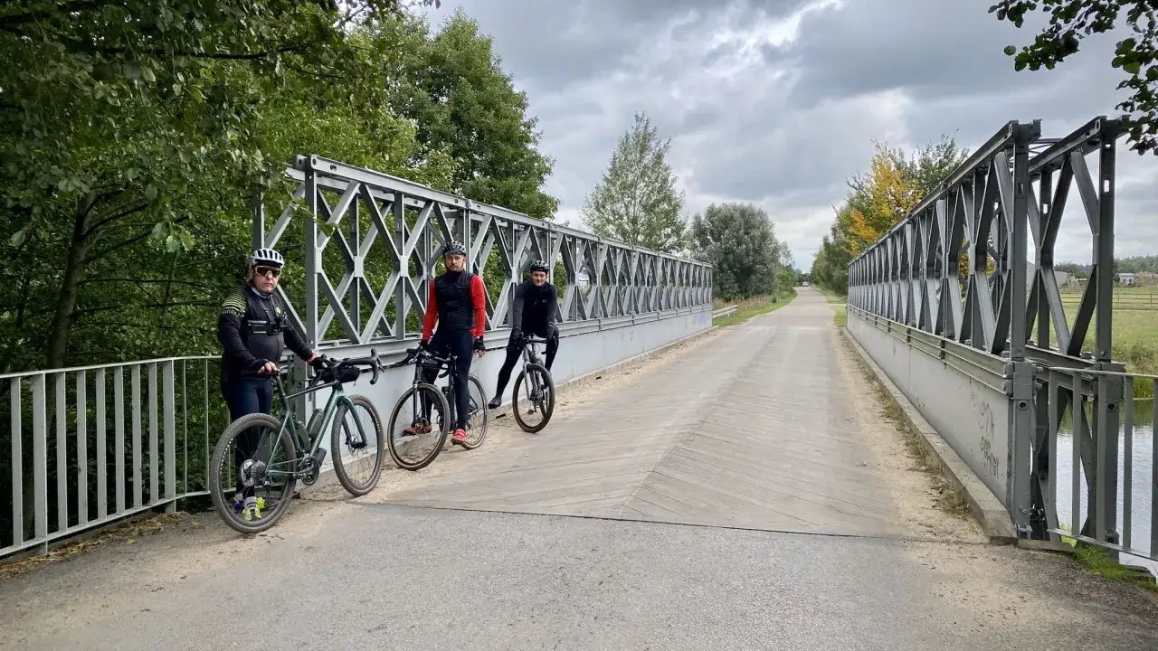 Trzech rowerzystów na moście, gotowych na mazowiecki gravel.