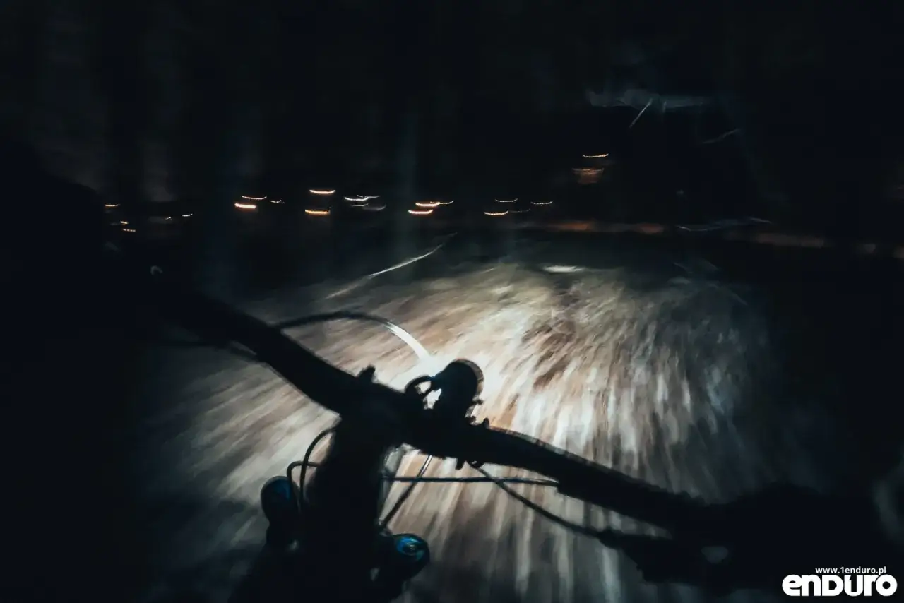 Widok z perspektywy rowerzysty nocą. Kierownica roweru i światło oświetlające drogę. Dobre jakie oświetlenie do roweru jest kluczowe dla bezpieczeństwa.