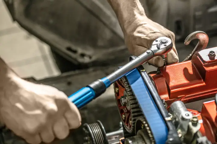 Mechanik używa klucza dynamometrycznego do precyzyjnego dokręcania śrub w silniku. To narzędzie jest kluczowe, by wiedzieć, klucz dynamometryczny co to i jak go używać.